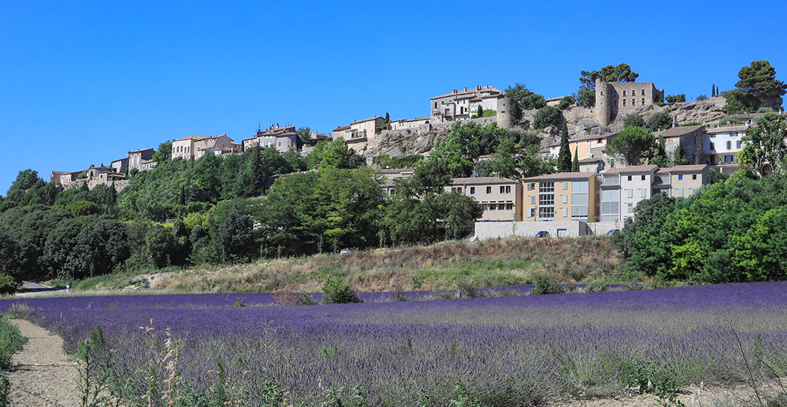 Village perche au dessus de champs de lavandes