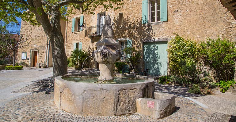Vieille fontaine sur une place village vacances à vélo en Provence