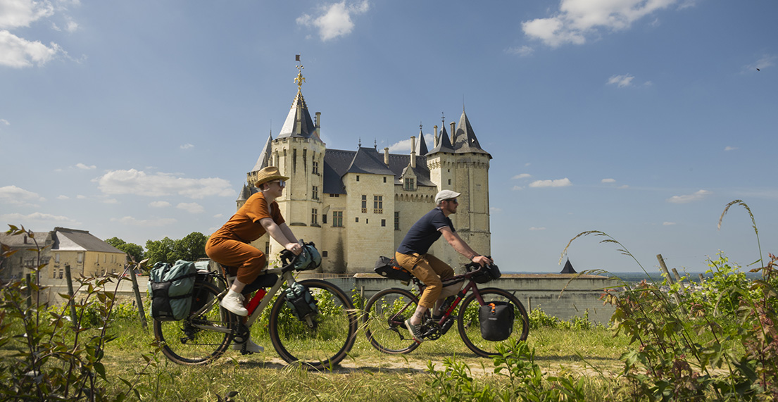 Un couple de cycliste roule devant le château de Saumur