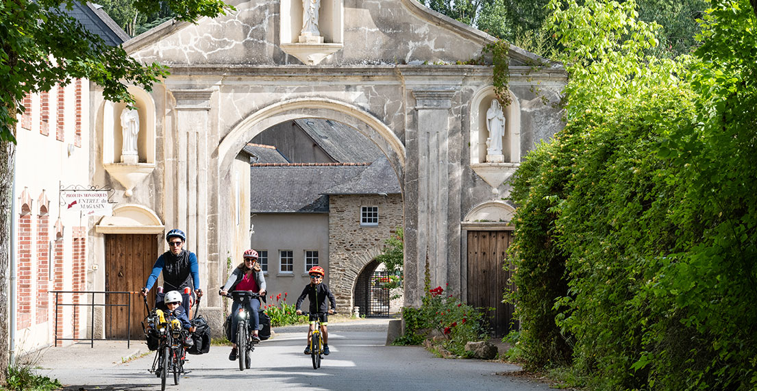 Une famille de cycliste roule sur une route bordée de verdure