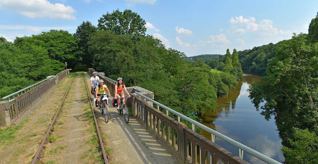 Une famille de cycliste traverse un pont, anciennement chemin de fer