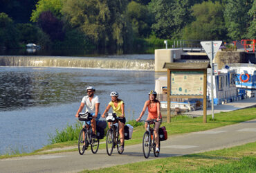 Un groupe de cycliste longe un canal et ses ecluses
