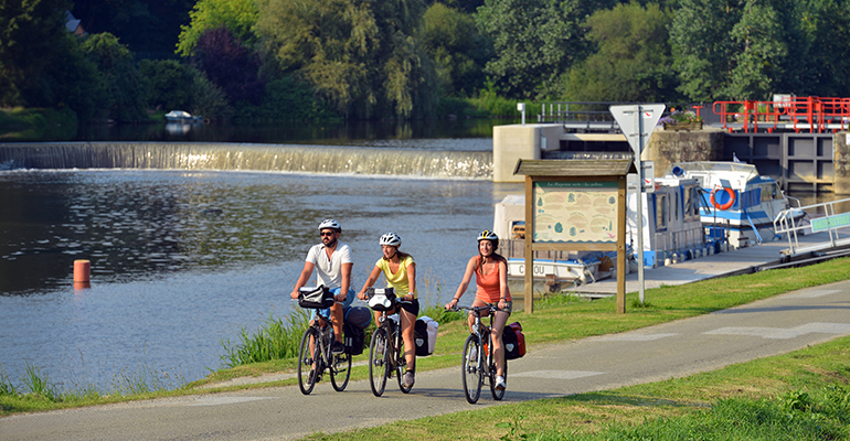 Un groupe de cycliste longe un canal et ses ecluses