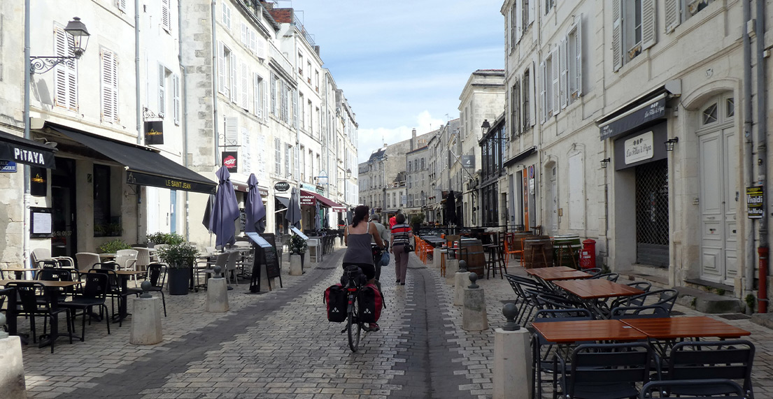Une cycliste roule sur les rues pavees de La Rochelle dans une rue commercante