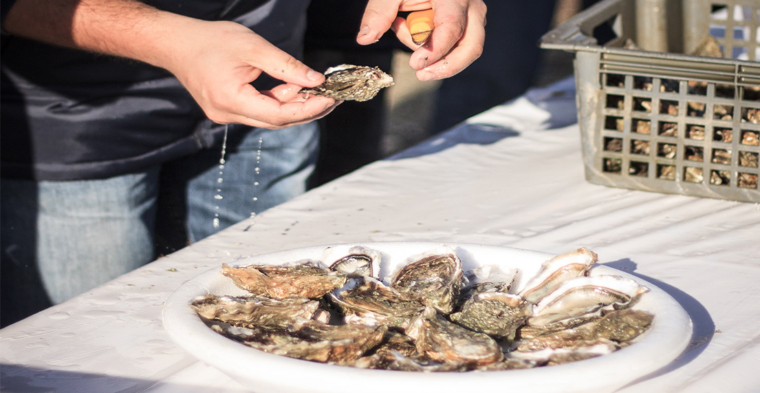 Une homme ouvre des huitres et les poses sur un plateau