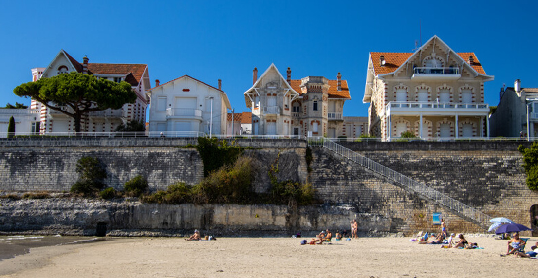 Des maisons se dressent devant une plage de sable blanc