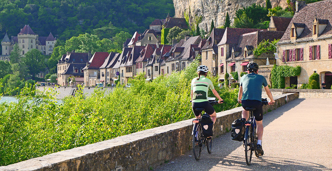 Un couple de cycliste se dirige vers les maisons troglodytes de La Roque-Gageac