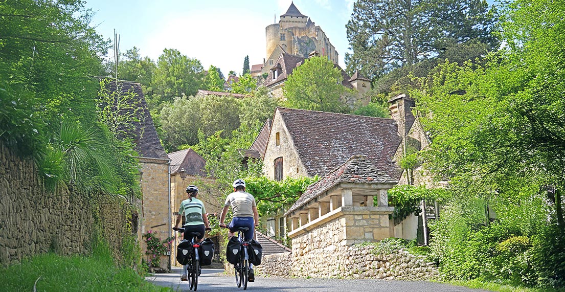 Un groupe de cycliste roule en direction d'un château perché