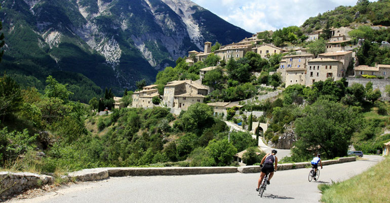 2 cyclistes descendent à vélo et arrivent dans un village