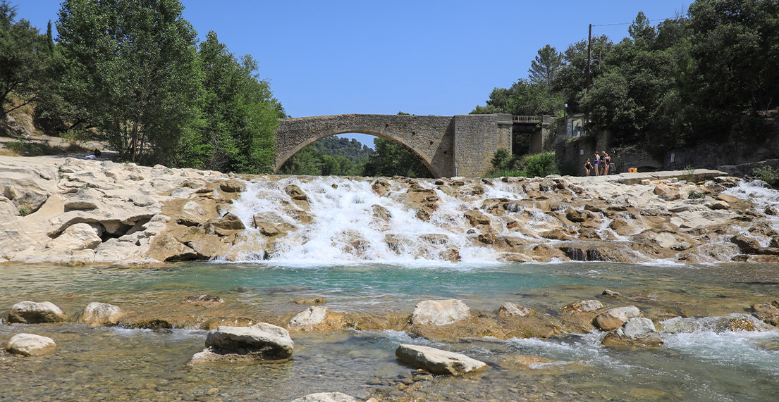 Un pont en pierre traverse d'une riviere d'eau turquoise