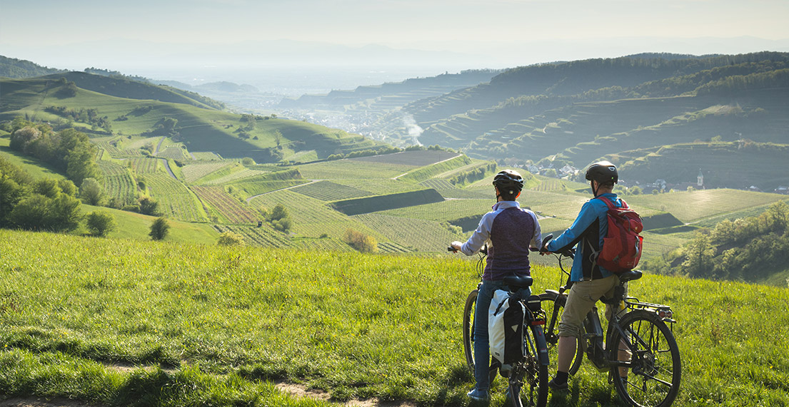 Un groupe de cyclistes roule dans les vignes et se dirigent vers un village