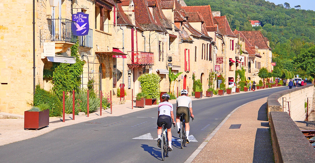 Un couple de cyclistes sur route traversent la Roque Gageac