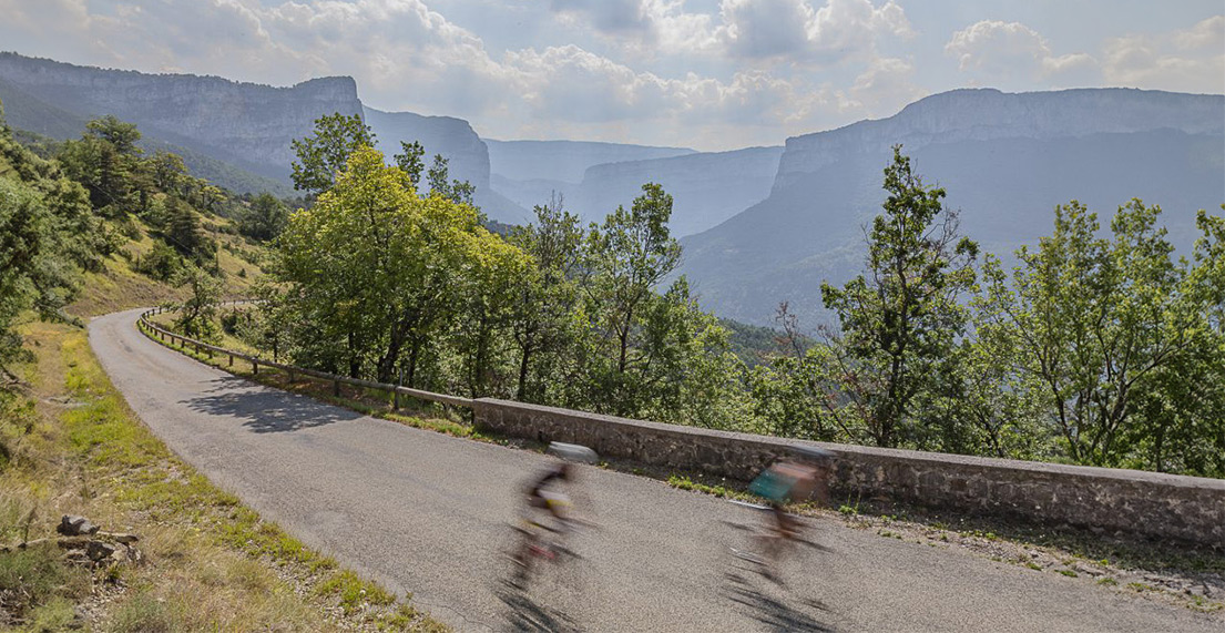 Deux cycliste roulent sur les routes entourées des montagnes du Vercors