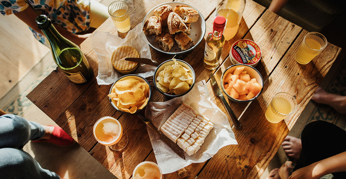 Une table remplie de produits gastronomiques normands : cidre, jus de pomme, pommes, fromage