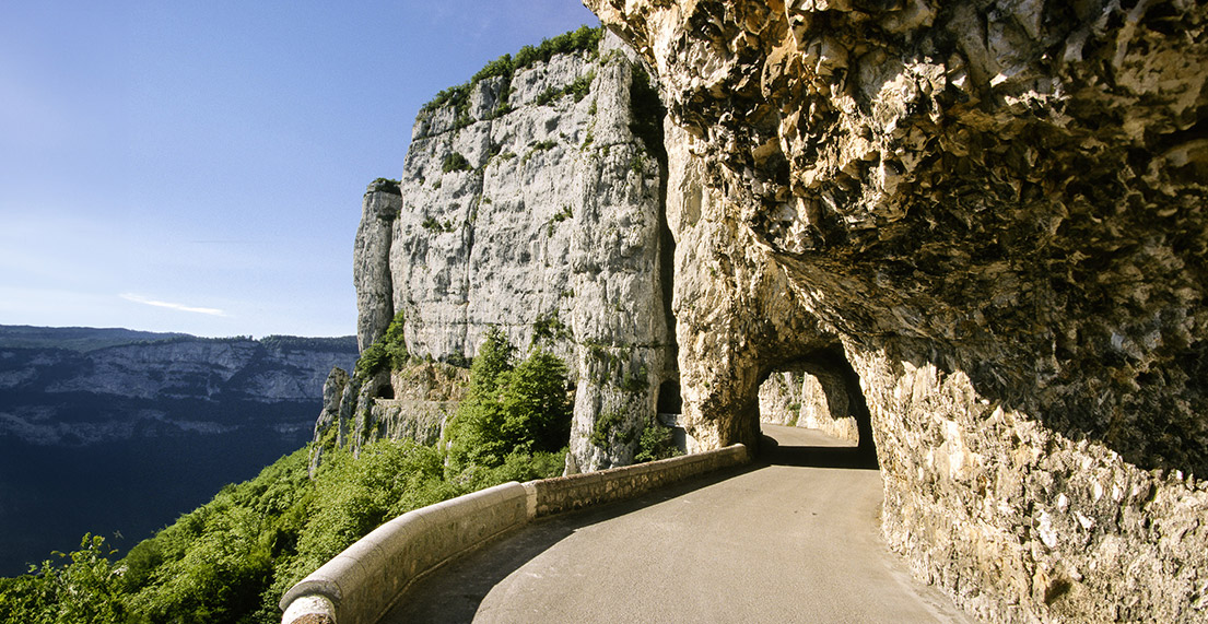 Une route de montagne passe dans un tunnel rocheux