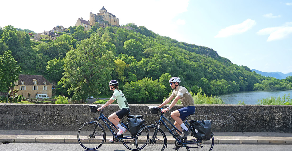 Un couple de cyclistes roule devant un chateau
