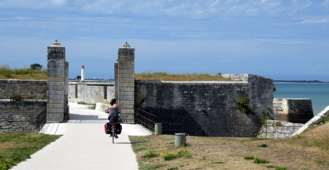 Une cycliste traverse une fortification en front de mer