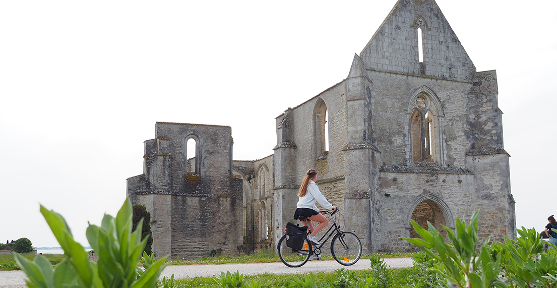 Une cycliste roule devant une vielle abbaye