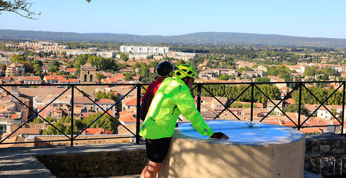 Un couple de cycliste devant une vue panoramique des toits de la ville d'Orange