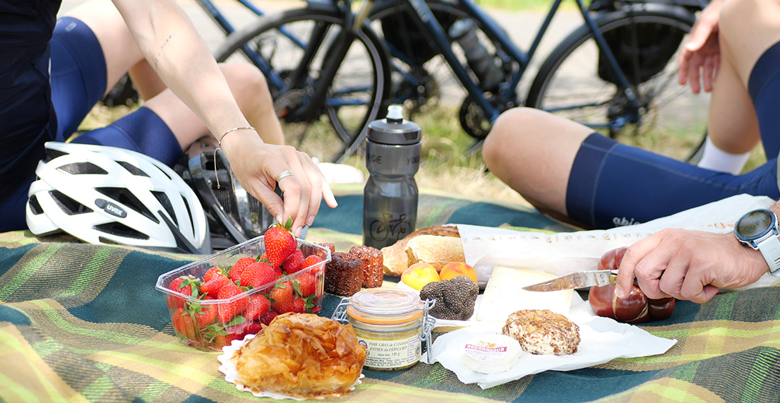 Un couple de cyclistes pique-nique avec des produits locaux