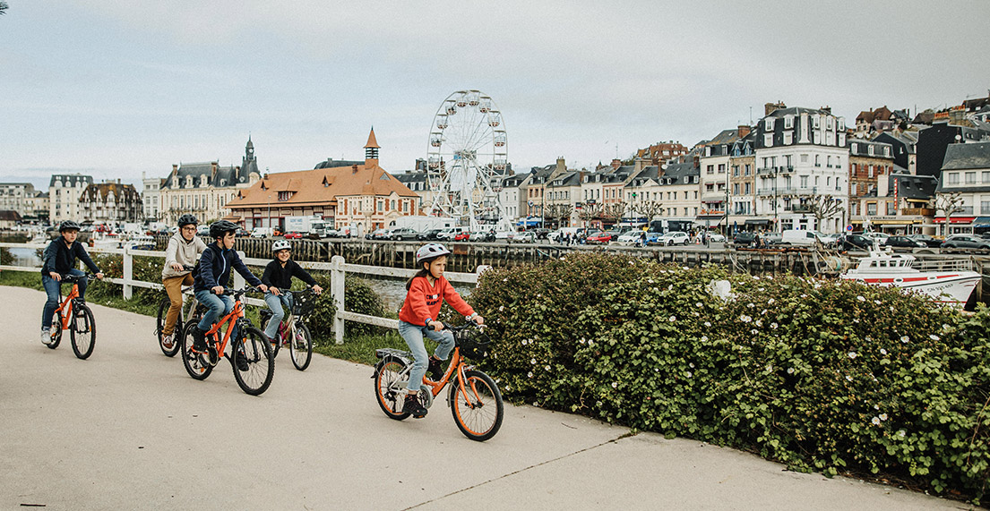 Une famille de cycliste roule dans la ville animée de Deauville et sa grande roue