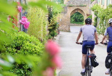 Deux cyclistes descendant une rue fleurie