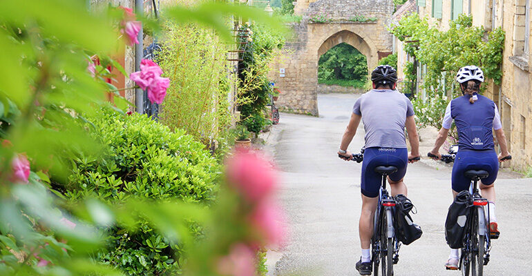 Deux cyclistes descendant une rue fleurie