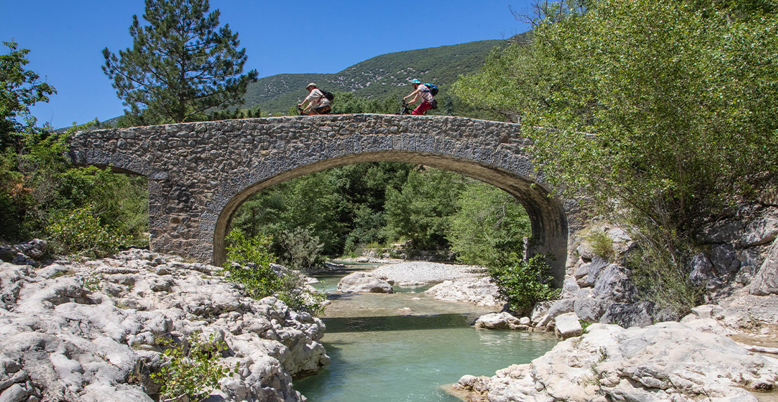 Deux cyclistes traversent un pont en pierres