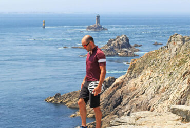 Un cycliste devant la pointe du Raz et son phare