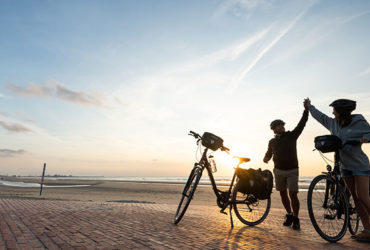 2 cyclistes sur une vaste plage, fiers d'être arrivés à destination