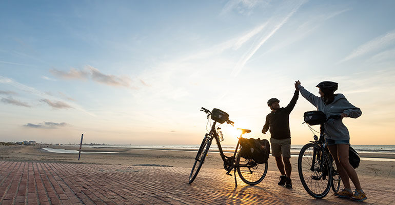 2 cyclistes sur une vaste plage, fiers d'être arrivés à destination