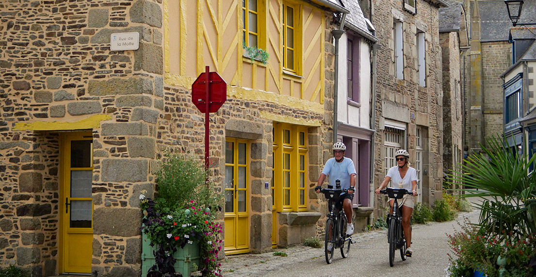 Un couple de cycliste traverse une ville aux maisons colorees a pants de bois