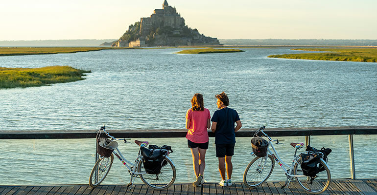 Cyclistes debout admirant le Mont Saint-Michel