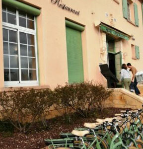 Façade de l'hôtel couleur beigne avec les fenêtre et portes en vert clair. Des vélos sont disposés devant