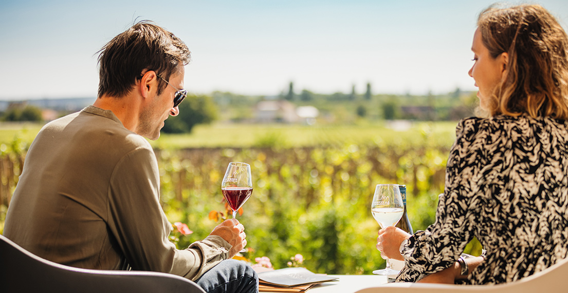Un couple deguste du vin devant un vignoble