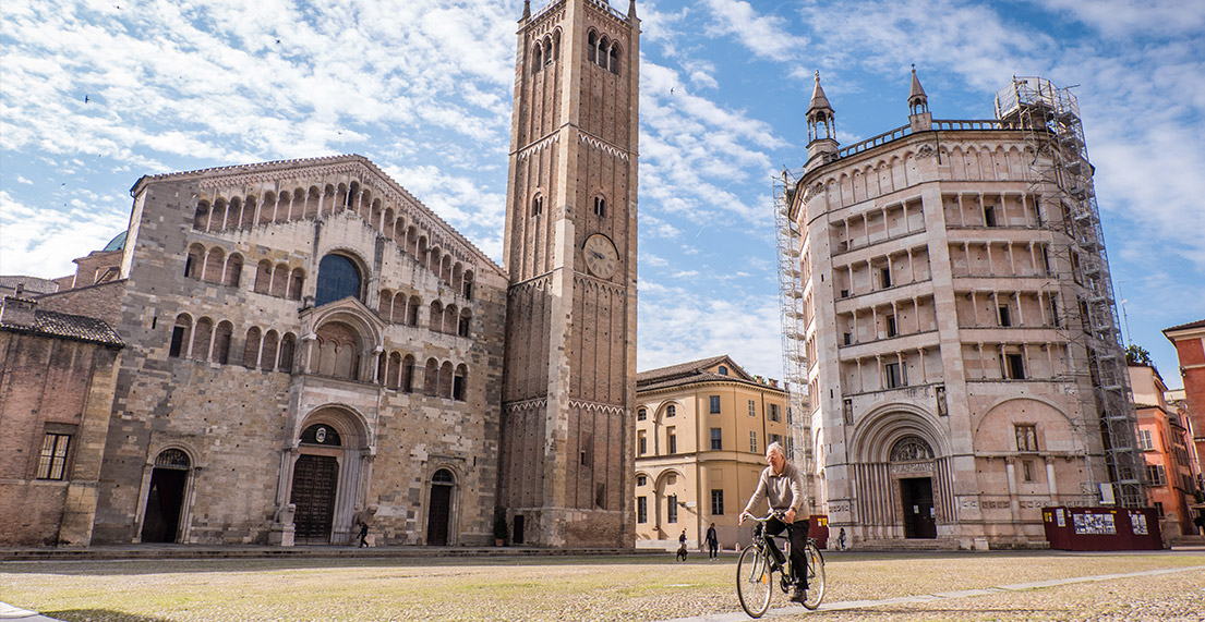 Un cycliste roule sur une place pavee de parme