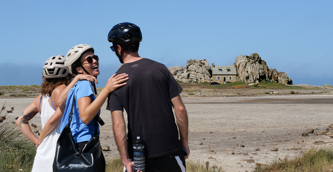 Un groupe de cycliste regarde la maison entre les rocher en bord de mer