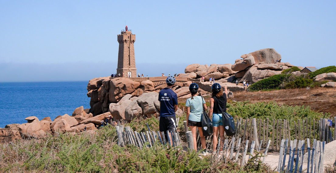 Un groupe de cycliste admire le phare rose de Ploumanach