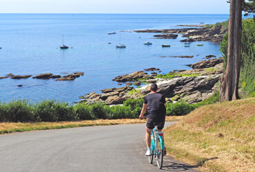 Un cycliste roule sur une route en direction de la mer et ses iles