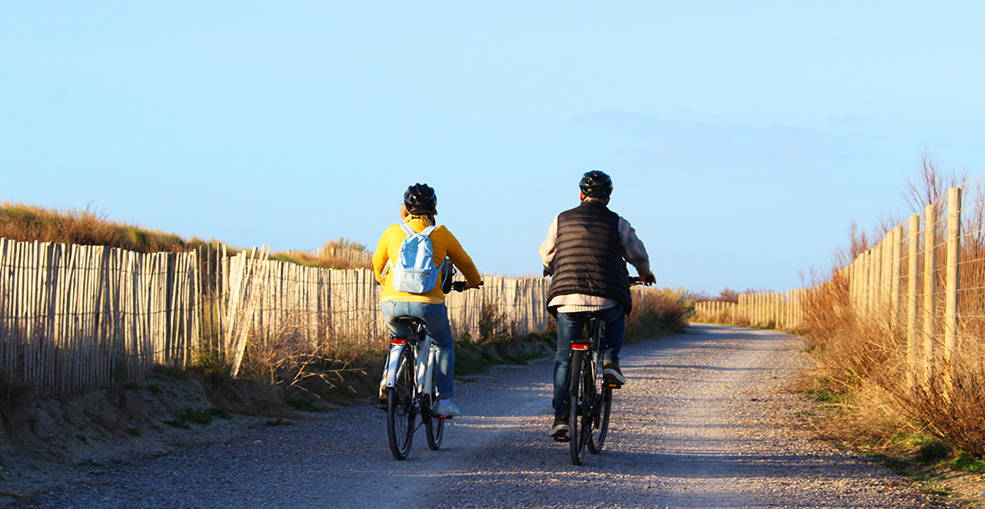 Un couple de cycliste roule sur un chemin cyclable en bord de mer