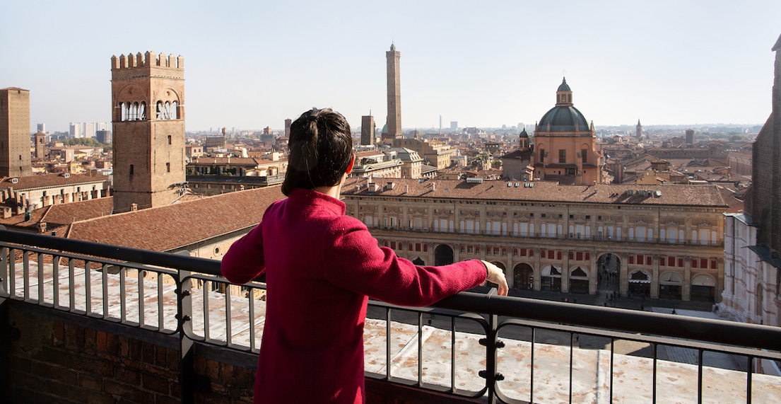Une femme admire une vue panoramique sur les batiments et tours de la ville de Bologne