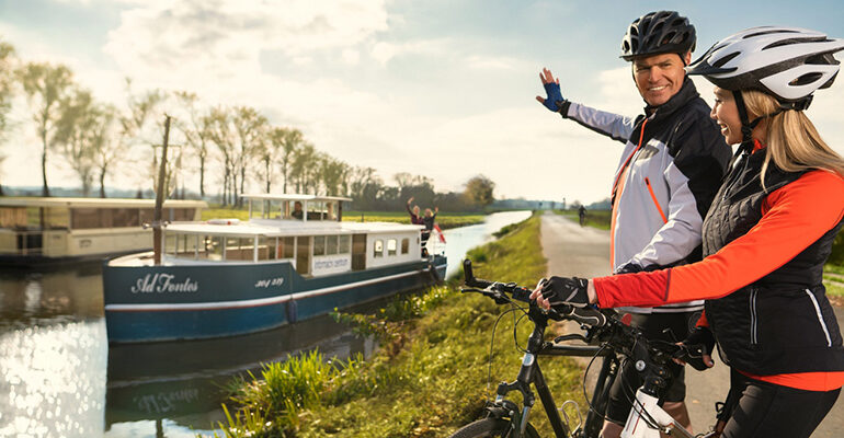 2 cyclistes regardent une péniche sur le canal