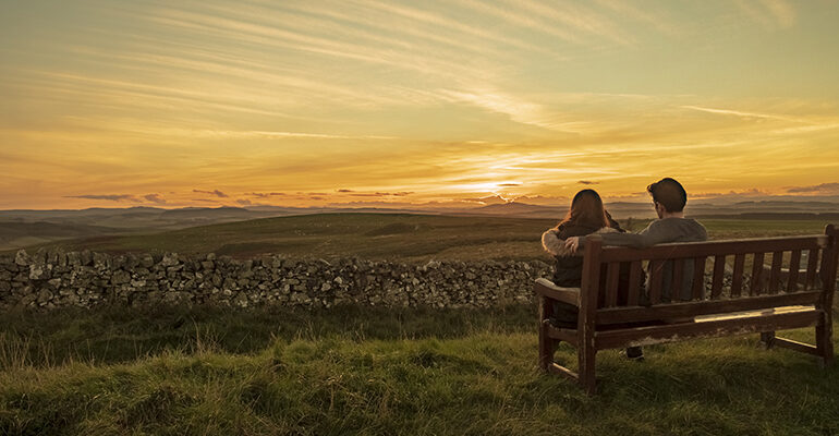 Un couple regarde le coucher de soleil sur les landes Écossaises