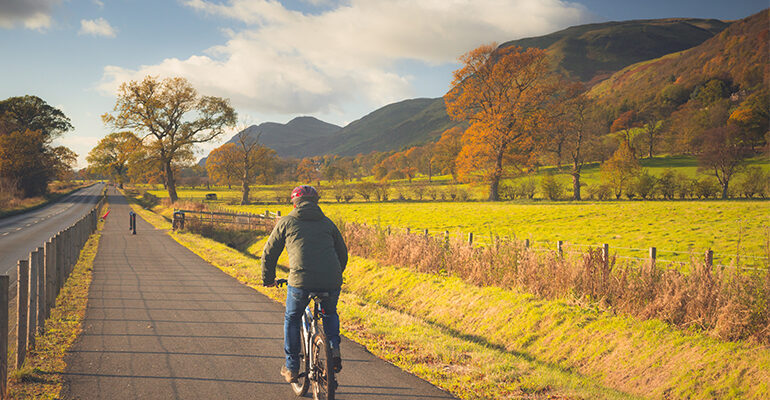 Cycliste sur une route cyclable au milieu d'un paysage montagneux