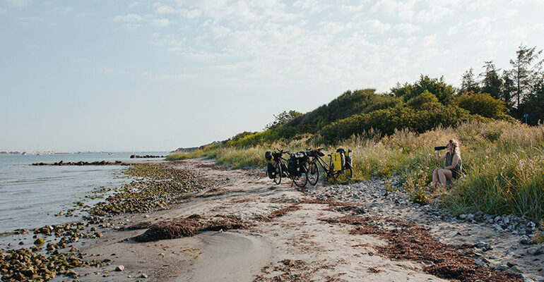 Une cycliste fait une pause boisson sur une plage