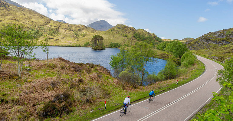 Deux cyclistes sur une route le long d'un lac