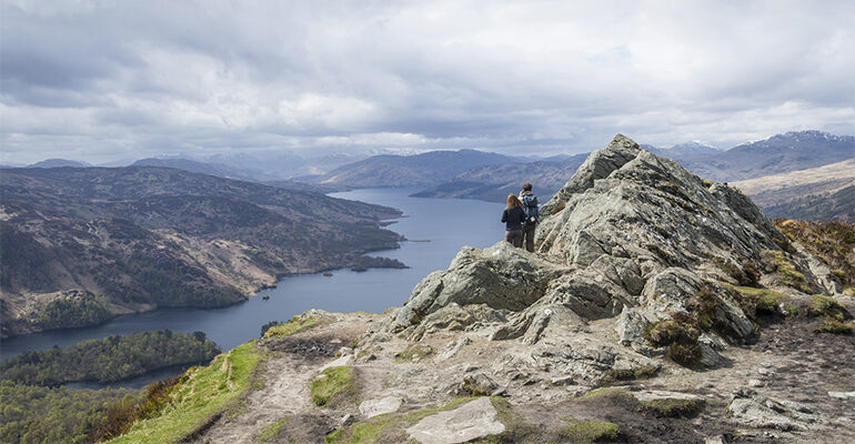 Un couple admire la vue d'un lac depuis une montagne