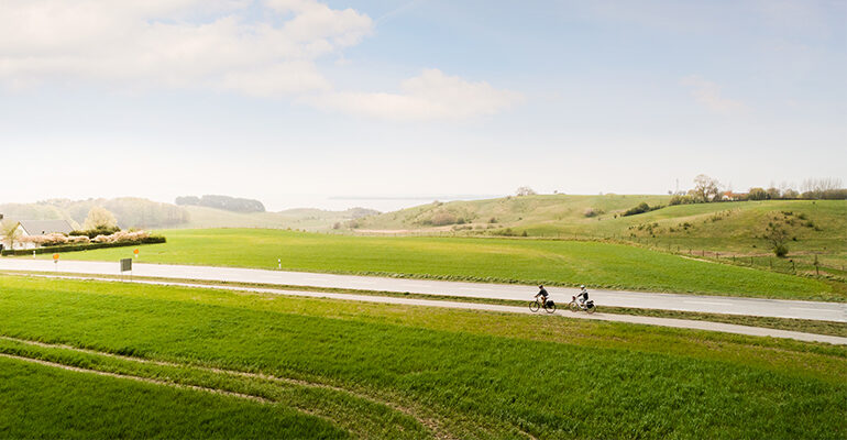 Deux cyclistes roulent sur une route de campagne verdoyante