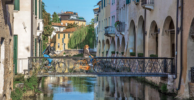 2 cyclistes traversent un pont à Trevise en Italie du Nord
