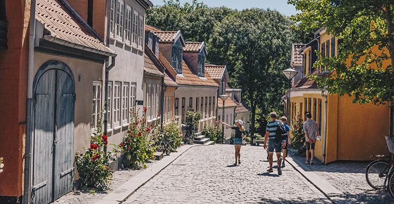 Des personnes marchent dans une rue pavée avec des maisons colorées